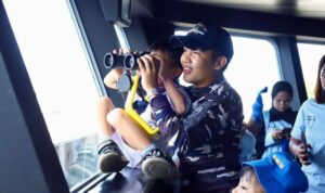 Seorang prajurit TNI AL membimbing seorang anak TK menggunakan teropong saat belajar pengenalan peralatan di KRI Teluk Calang-524. Foto Antara