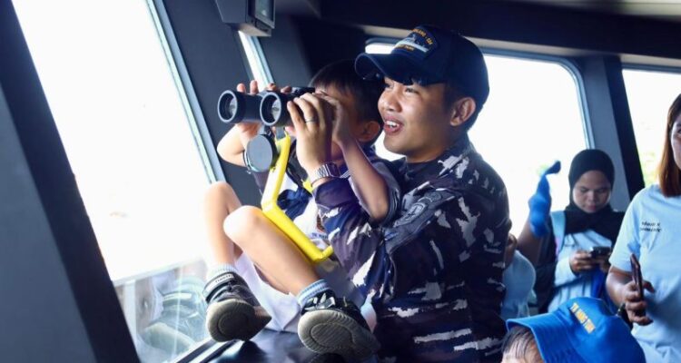 Seorang prajurit TNI AL membimbing seorang anak TK menggunakan teropong saat belajar pengenalan peralatan di KRI Teluk Calang-524. Foto Antara