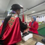 Dekan FKM Unhas Prof. Sukri Palatturi, SKM, M.Kes, M.Sc,PH., Ph.D menyerahkan tanda lulus doktor kepada Nanda Masraini Daulay setelah lulus ujian terbuka promosi doktor kesehatan masyarakat dengan predikat cumlaude. Foto Indomaritim.com/Haresti.