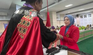 Dekan FKM Unhas Prof. Sukri Palatturi, SKM, M.Kes, M.Sc,PH., Ph.D menyerahkan tanda lulus doktor kepada Nanda Masraini Daulay setelah lulus ujian terbuka promosi doktor kesehatan masyarakat dengan predikat cumlaude. Foto Indomaritim.com/Haresti.