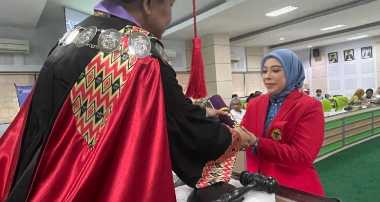 Dekan FKM Unhas Prof. Sukri Palatturi, SKM, M.Kes, M.Sc,PH., Ph.D menyerahkan tanda lulus doktor kepada Nanda Masraini Daulay setelah lulus ujian terbuka promosi doktor kesehatan masyarakat dengan predikat cumlaude. Foto Indomaritim.com/Haresti.