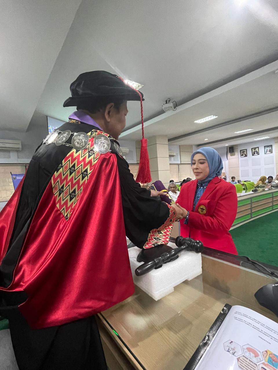 Dekan FKM Unhas Prof. Sukri Palatturi, SKM, M.Kes, M.Sc,PH., Ph.D menyerahkan tanda lulus doktor kepada Nanda Masraini Daulay setelah lulus ujian terbuka promosi doktor kesehatan masyarakat dengan predikat cumlaude. Foto Indomaritim.com/Haresti.