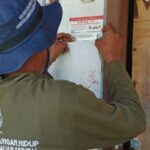 Petugas Suku Dinas Lingkungan Hidup Kabupaten Kepualan Seribu memasang stiker di rumah penduduk yang melakukan pemilahan sampah dari sumber. Foto Antara