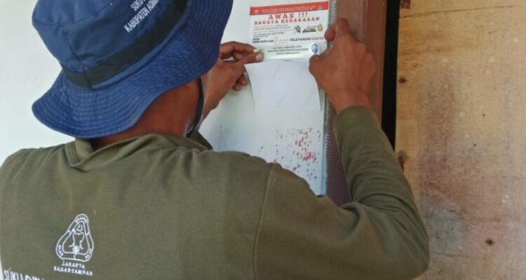 Petugas Suku Dinas Lingkungan Hidup Kabupaten Kepualan Seribu memasang stiker di rumah penduduk yang melakukan pemilahan sampah dari sumber. Foto Antara