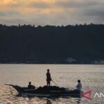 Nelayan Teluk Ambon, La Hamid (48) mendorong perahunya untuk melaut di Teluk Ambon. Foto Antara