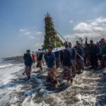Abdi dalem membawa gunungan hasil bumi menuju pantai saat prosesi labuhan di Pantai Glagah, Kulon Progo, Yogyakarta, Rabu (17/7/2024). Tradisi yang digelar oleh Kadipaten Pakualaman yang rutin dilaksanakan pada bulan Muharram atau Suro tersebut melabuh (melarung) sejumlah sesaji dan barang milik KGPAA Paku Alam X sebagai bentuk rasa syukur keluarga besar Puro Pakualaman kepada Tuhan Yang Maha Esa. Foto Antara