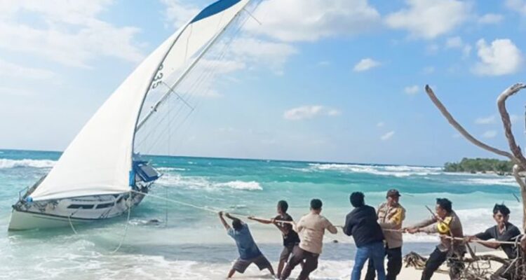 Aparat kepolisian dan warga menambatkan yacht tanpa pemilik yang terdampar di perairan Rote Ndao. Foto Antara