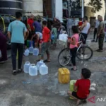 Warga Palestina mengisi wadah dengan air bersih yang didistribusikan melalui pasokan truk tangki di Khan Yunis, Gaza, Palestina, Senin (13/7/2026). Krisis air masih berlangsung akibat kerusakan parah pada infrastruktur dan sumur air yang disebabkan oleh serangan Israel. Sumber Foto: Antara