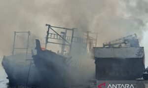 Petugas memadamkan kapal terbakar saat sandar di Dermaga Muara Angke, Jakarta Utara, Minggu (19/7/2026). Sumber foto: Antara Petugas memadamkan kapal terbakar saat sandar di Dermaga Muara Angke, Jakarta Utara, Minggu (19/7/2026). Sumber foto: Antara