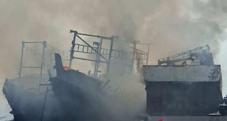 Petugas memadamkan kapal terbakar saat sandar di Dermaga Muara Angke, Jakarta Utara, Minggu (19/7/2026). Sumber foto: Antara
