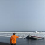 Petugas Basarnas Pos SAR Jember menunjukkan bangkai perahu yang terbalik di Pantai Paseban Jember, Rabu (19/8/2026). Sumber foto: Antara