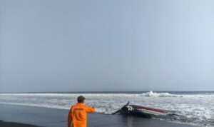 Petugas Basarnas Pos SAR Jember menunjukkan bangkai perahu yang terbalik di Pantai Paseban Jember, Rabu (19/8/2026). Sumber foto: Antara