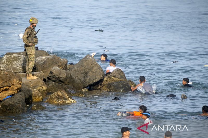 Petugas keamanan Spanyol berjaga saat para migran yang berenang dari Maroko tiba di pantai kota Ceuta, Spanyol, Jumat (31/7/2026). Sumber foto: Antara Petugas keamanan Spanyol berjaga saat para migran yang berenang dari Maroko tiba di pantai kota Ceuta, Spanyol, Jumat (31/7/2026). Sumber foto: Antara