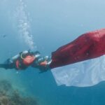 Sejumlah personel Kantor Pencarian dan Pertolongan (Basarnas) Kupang melaksanakan upacara HUT RI di bawah laut di perairan Kupang, Senin (17/8/2026). Sumber foto: Antara