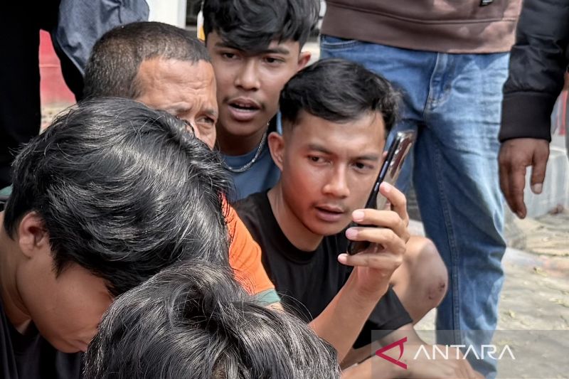 Akmal (kanan) bersama ABK lain yang bekerja di KM Virgo Transport 8 yang mengalami kecelakaan, menghubungi keluarga melalui telepon seluler setelah berhasil dievakuasi di Pelabuhan Trisakti, Banjarmasin, Kalimantan Selatan, Selasa (15/9/2026). Sumber foto: Antara