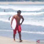 Atlet selancar putra Indonesia I Made Pajar Ariyana berjalan membawa papan selancar usai mengikuti latihan jelang Asian Games Aichi-Nagoya 2026 di Pantai Kuta, Badung, Bali, Rabu (16/9/2026). Sumber foto: Antara