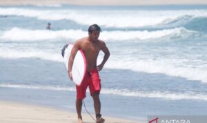 Atlet selancar putra Indonesia I Made Pajar Ariyana berjalan membawa papan selancar usai mengikuti latihan jelang Asian Games Aichi-Nagoya 2026 di Pantai Kuta, Badung, Bali, Rabu (16/9/2026). Sumber foto: Antara