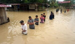 Sejumlah warga berjalan menerobos banjir di Kampung Baru, Lhoksukon, Aceh Utara, Aceh, Minggu (9/10/2022). Sumber foto: Antara