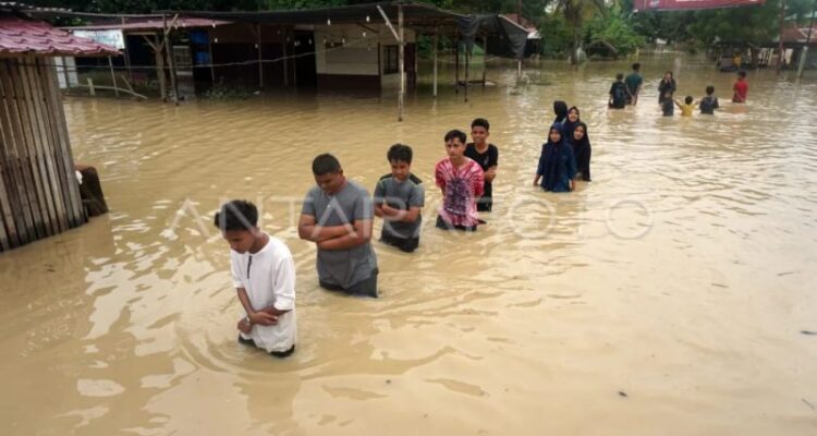 Sejumlah warga berjalan menerobos banjir di Kampung Baru, Lhoksukon, Aceh Utara, Aceh, Minggu (9/10/2022). Sumber foto: Antara
